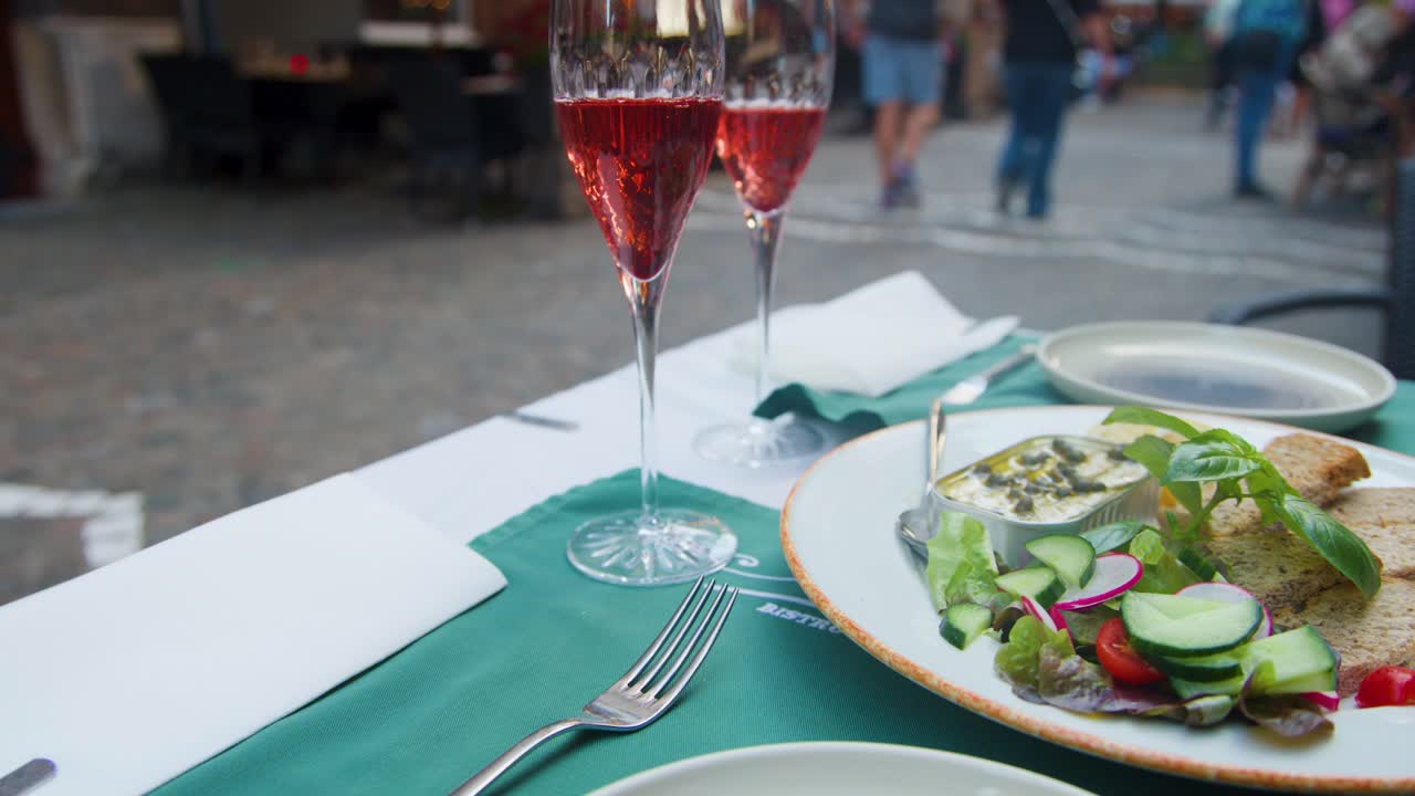 Fresh salad and sparkling cocktails on restaurant table, evening street scene, shallow depth of field