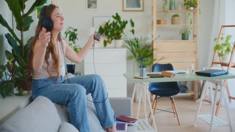 Happy-Woman-Dancing-to-Music-on-Sofa