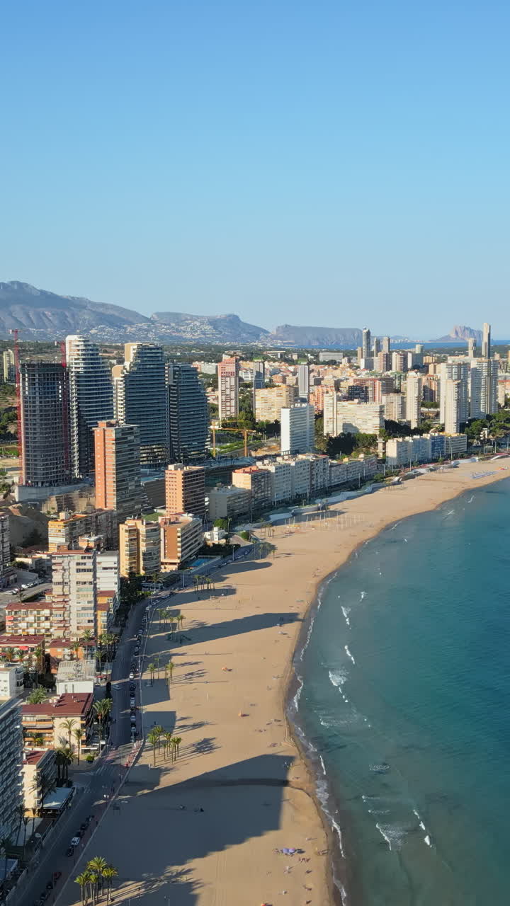 Aerial drone view of the buildings along the coastline and the sea in Benidorm, Spain in daylight. Vertical