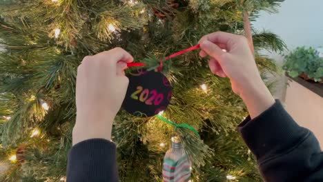 small hands putting up a 2020 handmade christmas ornament