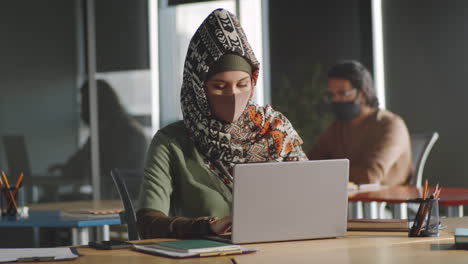 Mujer-De-Negocios-Con-Hiyab-Y-Máscara-Trabajando-En-Una-Laptop