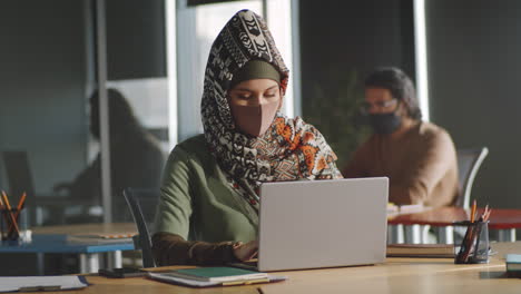 mulher de negócios em hijab e máscara trabalhando em laptop