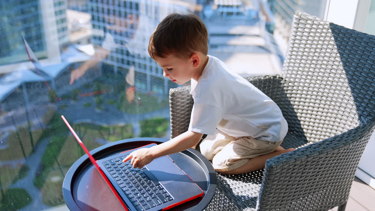 Child with laptop in modern space. A young child sits on a chair, focused on a laptop with a city view in the background, engaged in learning or playing