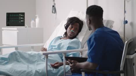 a young african-american male doctor is talking to a patient. a black woman patient talks to a doctor