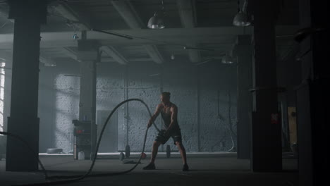 bodybuilder training with battle ropes. man performing strength exercises