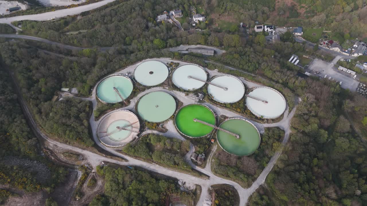 Top-down view of circular water-treatment basins, pipes and service lanes managing quarry runoff, conveying environmental infrastructure and resource-management engineering