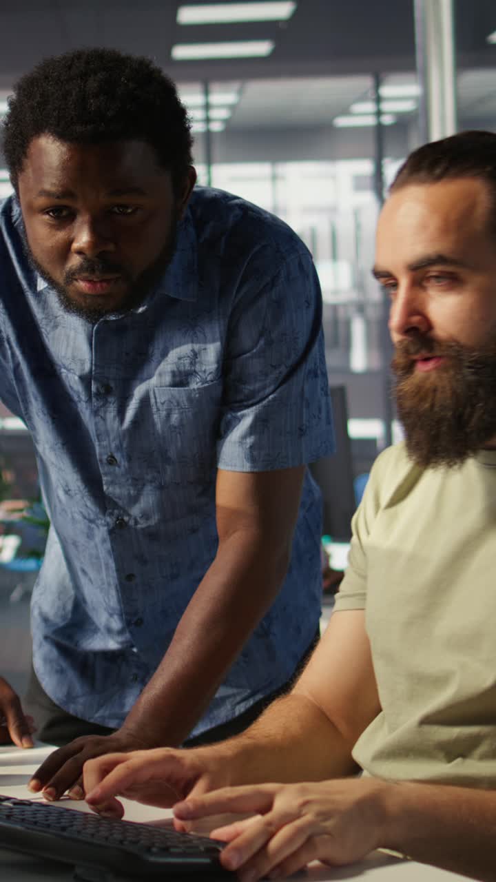 Vertical video Employee using computer to analyze datasets, being assisted by helpful coworker