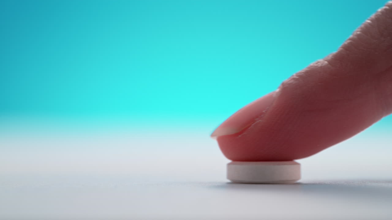 두통에 대한 아스피린을 주고, 알약은 하 테이블을 가로질러 파란 바탕에 매크로와 느린 동작으로 손가락으로 미끄러집니다.