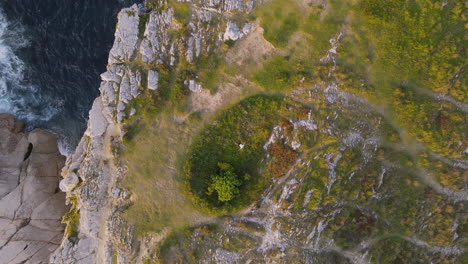 zoom in of a man lying and relaxing on the edge of a cliff of a rocky coastline