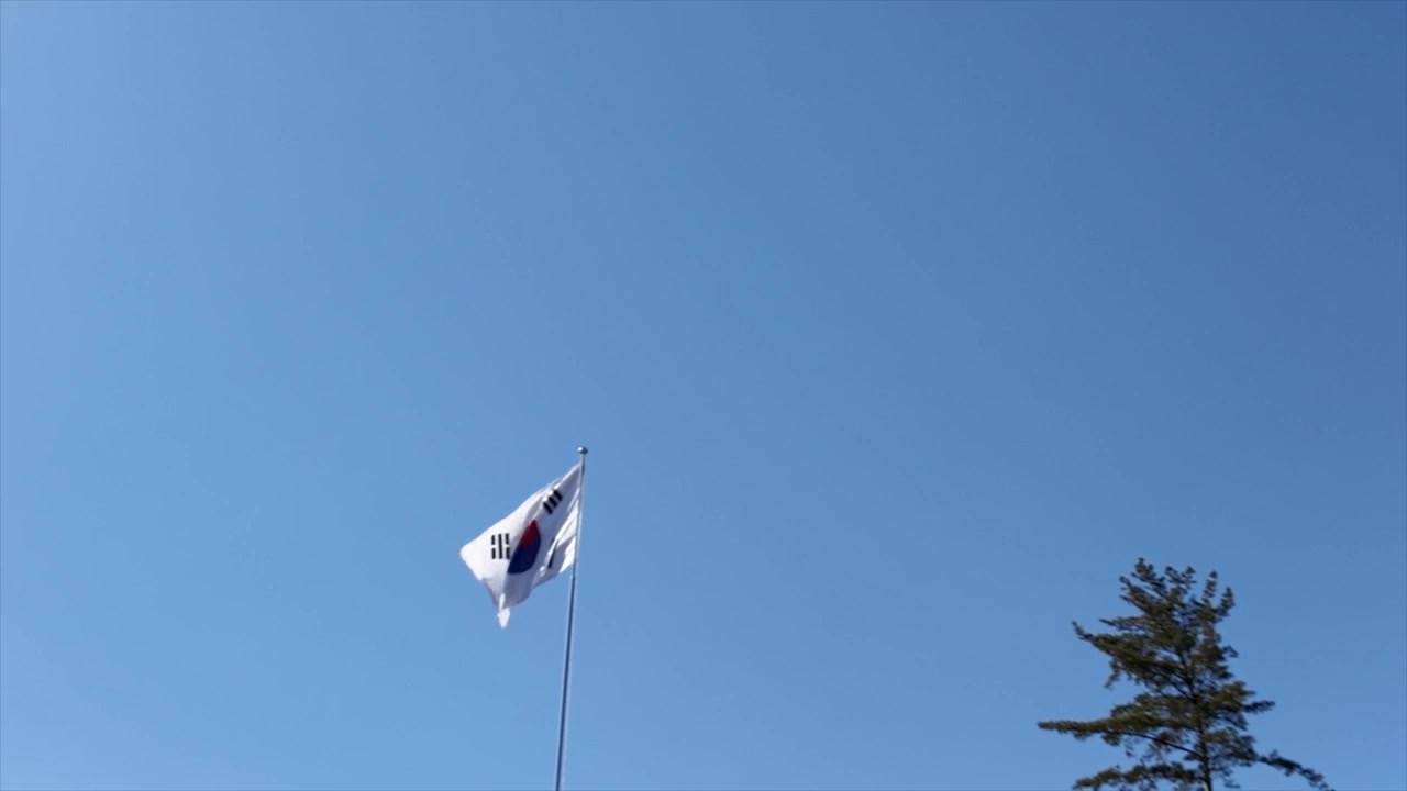 Rekaman close-up bendera nasional Korea Selatan berkibar anggun di tiang bendera. Sebuah bidikan bersih dan simbolis yang mewakili Korea Selatan