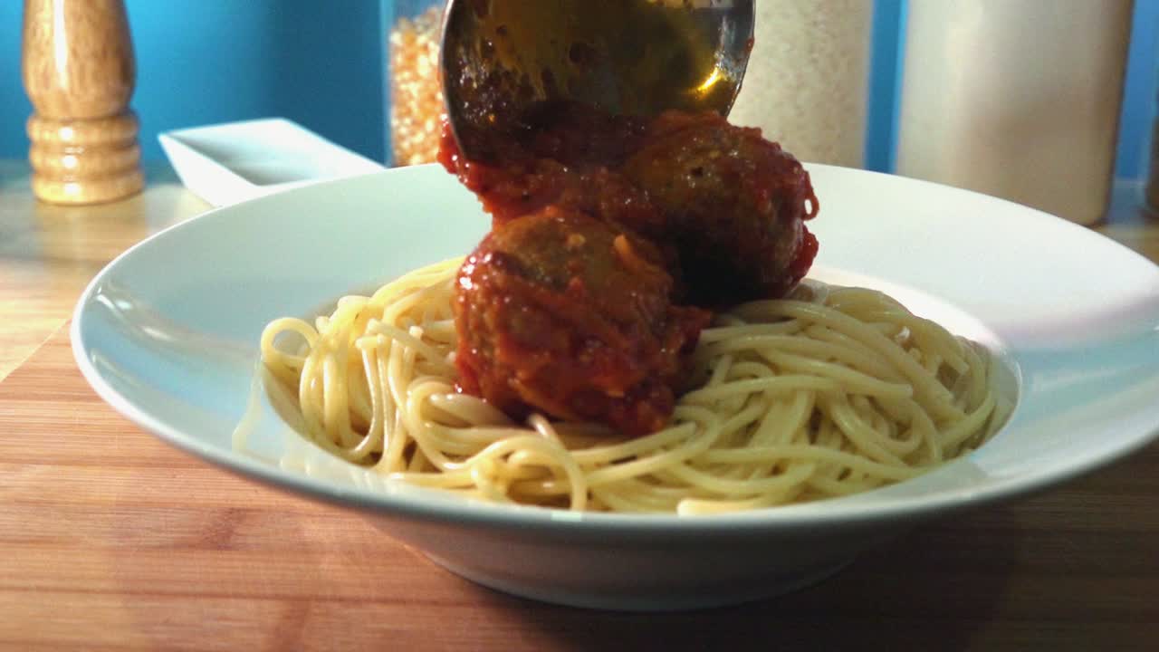 부엌 카운터에 있는 스파게티에 신선한 홈메이드 미트볼을 추가하는 중