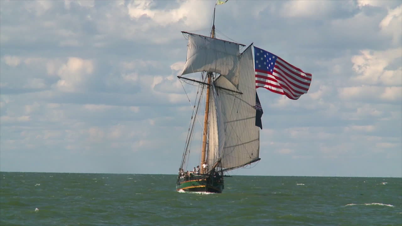 19세기 높이의 돛대가 달린 클리퍼선이 미국 국기를 휘날리며 공해를 항해합니다.