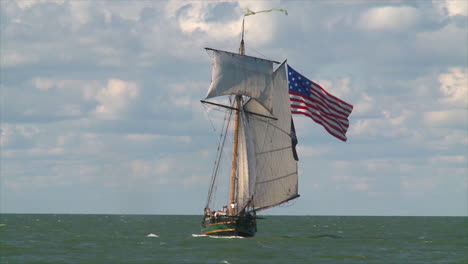 a 19th century tall masted clipper ship sails on the high seas flying an american flag