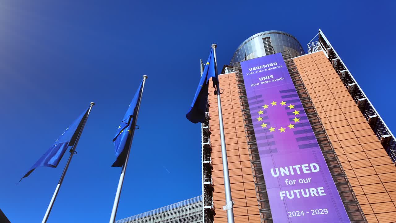 Bandiere dell'UE che sventolano fuori dall'edificio Berlaymont con uno slogan politico.