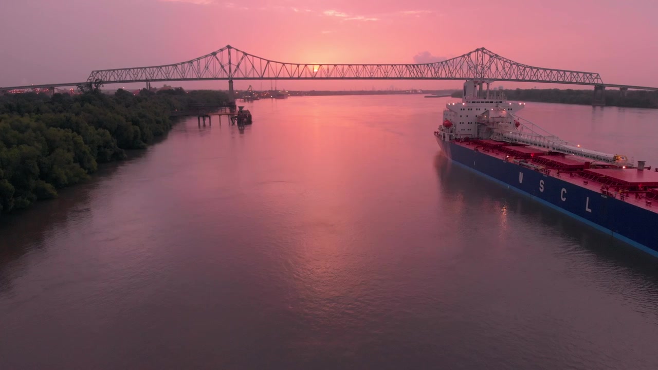Adelantamiento: barcaza anclada en el río Misisipi al amanecer con puente en el horizonte