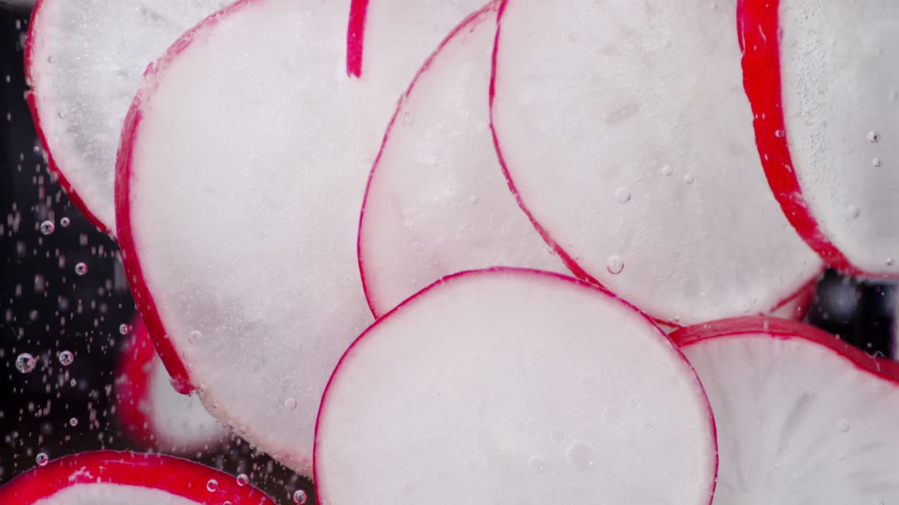 Sliced fresh radish under water with air bubbles.