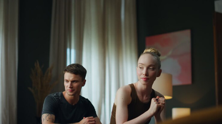 Woman squatting man together in room. Young sporty couple exercising at home.