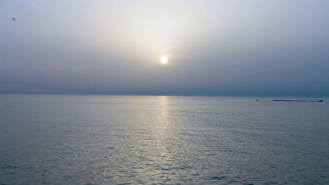 calm water waves on the sea ocean over misty clouds sky background on the sunrise morning