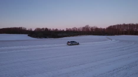 Drone-Siguiendo-La-Conducción-Del-Vehículo-En-La-Carretera-De-Hielo-Nevado-Explorando-Los-Paisajes-Locales-En-Invierno