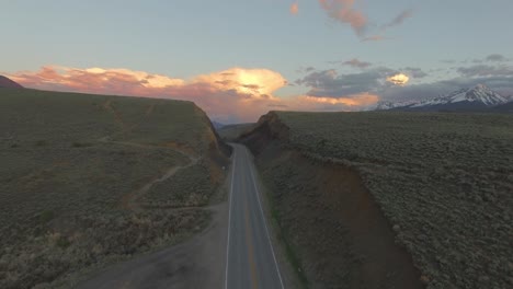 beautiful sunset establishing shot over mountain hillside in snow covered rocky mountains and road