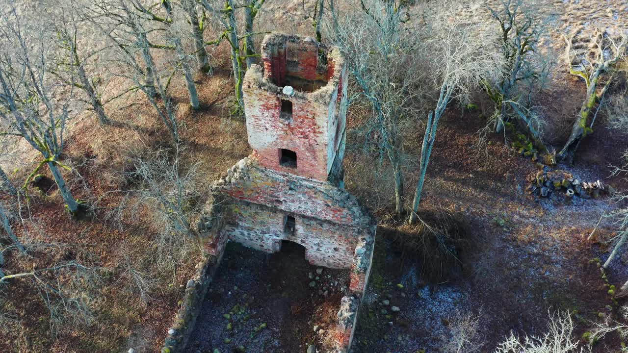 Luftfoto av ruiner av et gammelt forlatt kirkeklokketårn med et hull blant nakne trær