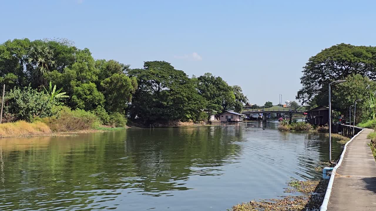 Canale Khlong a Pathum Thani con passerella pedonale in cemento sopraelevata lungo il corso d'acqua.