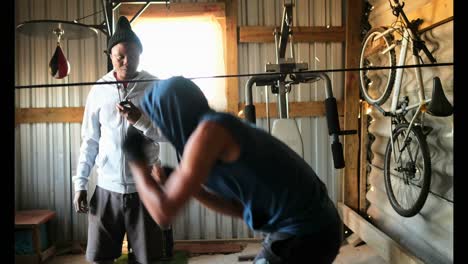 African-American-male-boxer-practicing-boxing-with-trainer-in-fitness-studio-4k