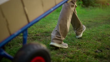 Agronomist-legs-walking-garden-using-wheelbarrow-box-equipment-in-plantation.