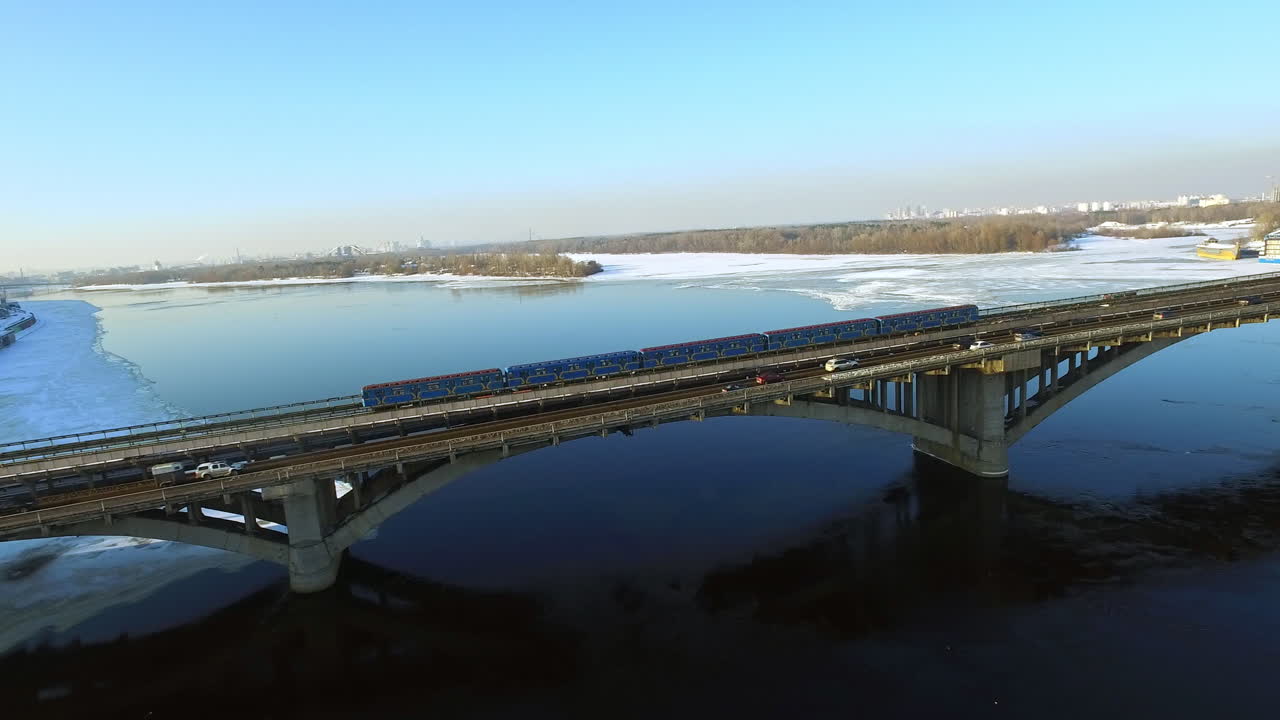 겨울에 교량 철도를 타고 있는 드론 뷰 에트로 열차. 고속도로의 자동차 교통