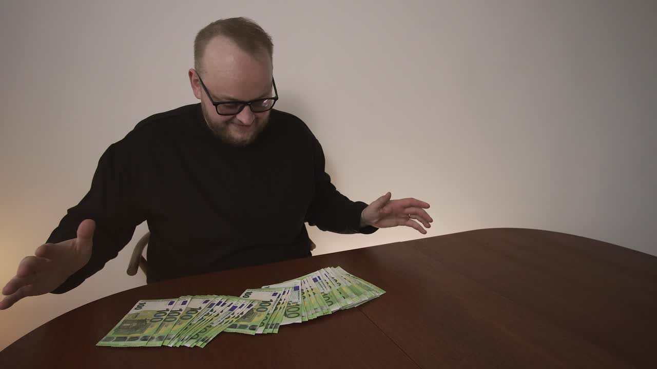 Uomo sorride mentre guarda una grande quantità di banconote in euro sul tavolo. Concetto di grandi guadagni, affare di successo e successo finanziario.