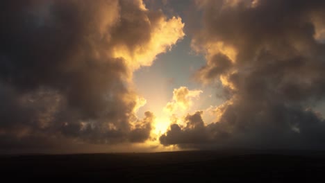 clouds gathering around rising sun at dawn sunrise with contrasting colors of blue and orange. aerial drone footage 4k.