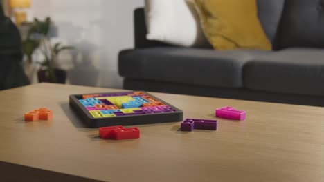 person tidying coloured interlocking shape puzzle on table at home for child diagnosed with asd 1