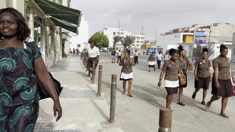 first-person view of creole workers walking along sidewalk in sal rei, cape verde, heading home after shift. the bustling street captures local life, urban charm, and vibrant community dynamics