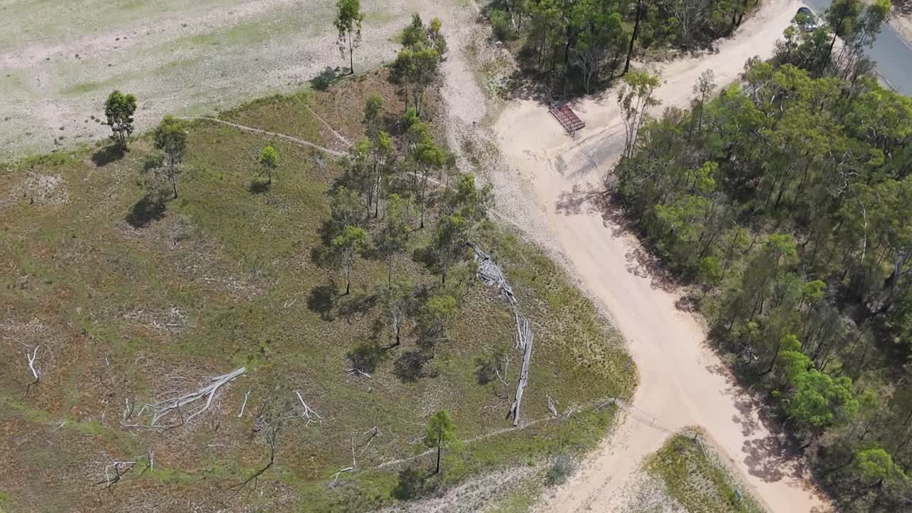 Aerial footage showcasing intersecting dirt roads and surrounding greenery in a rural landscape.