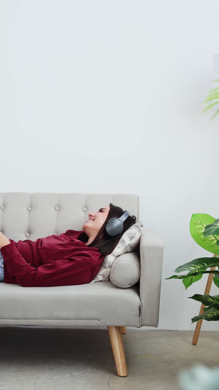 Giovane donna che si rilassa sul divano con cuffie e smartphone