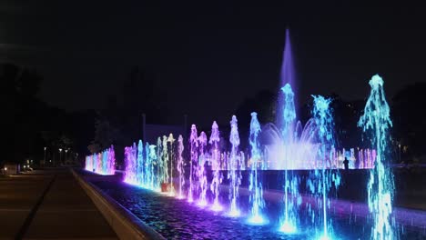 Fountain-illuminated-at-night,-abstract-lights-with-changing-colors-from-multiply-nozzles-set-in-a-line