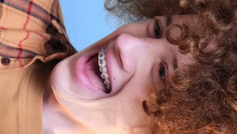 cute young happy student on blue background looking at phone cute young happy student on blue background looking at phone curly redhaired guy is crazy happy internet search technologies