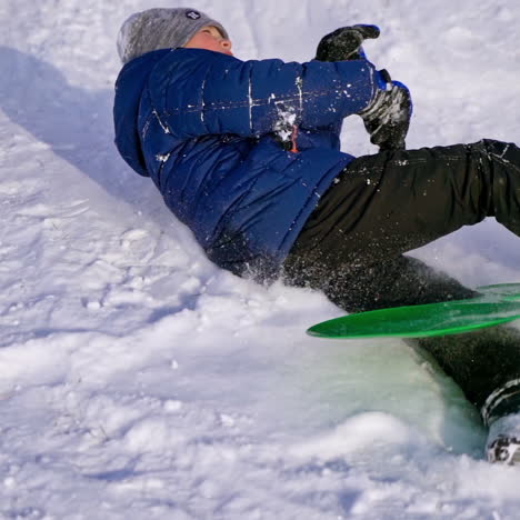 view from below on a boy sledding. cute child riding from snow slide in winter. cheerful vacation. slow motion.