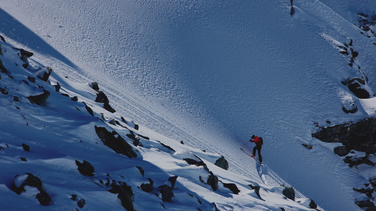 A professional skier hikes up a steep ridge in Verbier, then drops into an epic freeride descent. Pure adventure skiing in deep snow, dramatic terrain, and breathtaking alpine scenery.