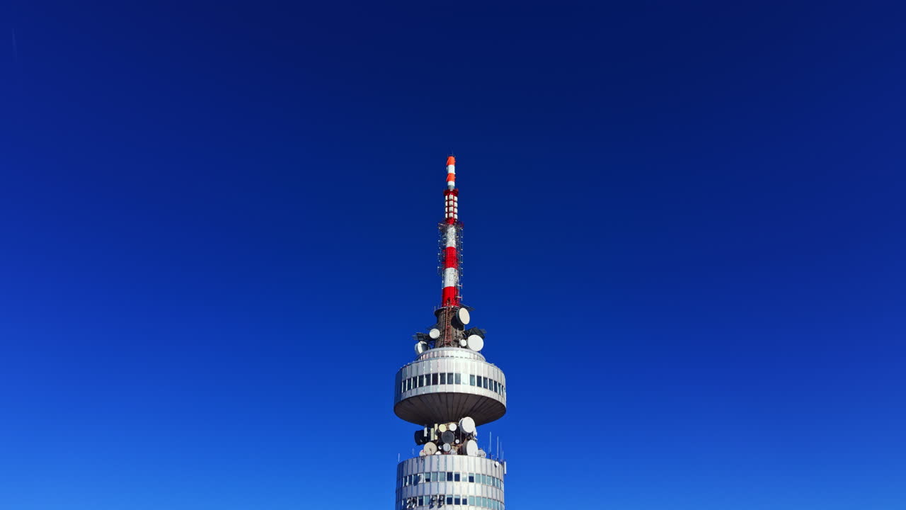 Alta Torre de Comunicación con Panorámica Ascendente contra un Cielo Azul Despejado