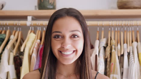 retrato de una cliente o propietaria de pie junto a estantes de ropa en una tienda de moda independiente