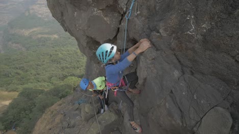 a young indian girl attempting to rock climb a beautiful pinnacle on sunny day