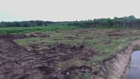 aerial shot of soon to be construction site with wholes in the ground with water in them and trees around