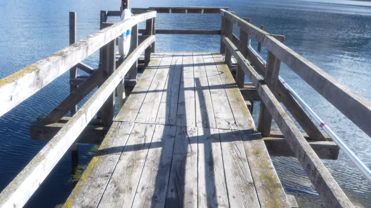 Wooden pier leading into a calm alpine lake surrounded by snowy mountains in the Engadin valley, Switzerland