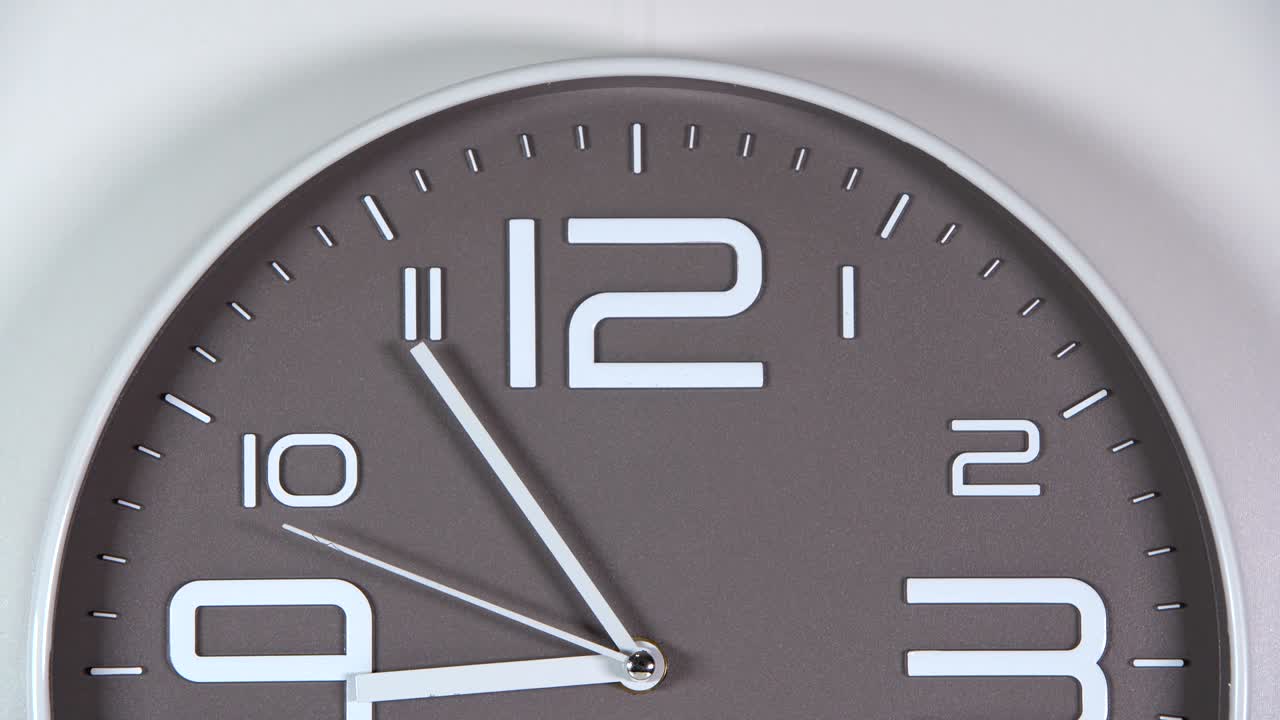 reloj de pared en un fondo gris. 08:55