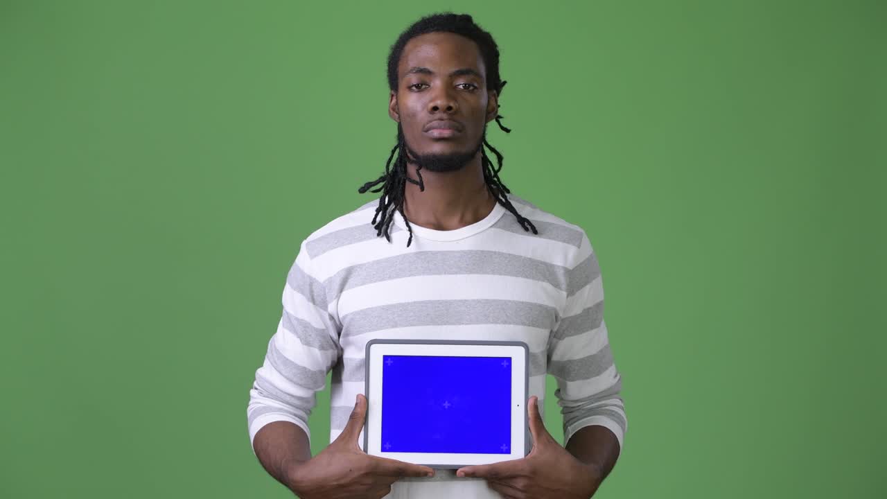 Young handsome African man with dreadlocks against green background