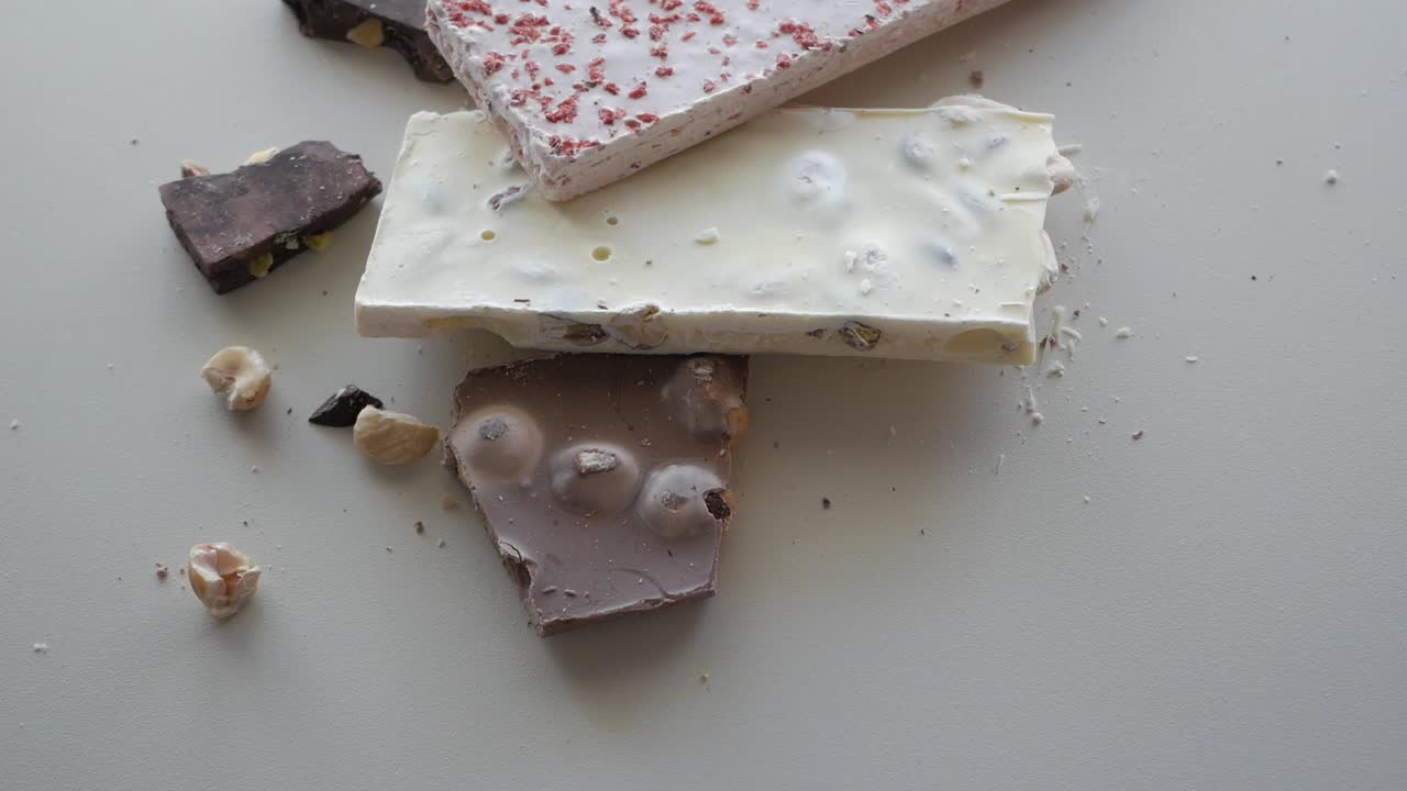 A variety of handcrafted chocolates in dark and white, garnished with nuts, beautifully presented on a white surface.