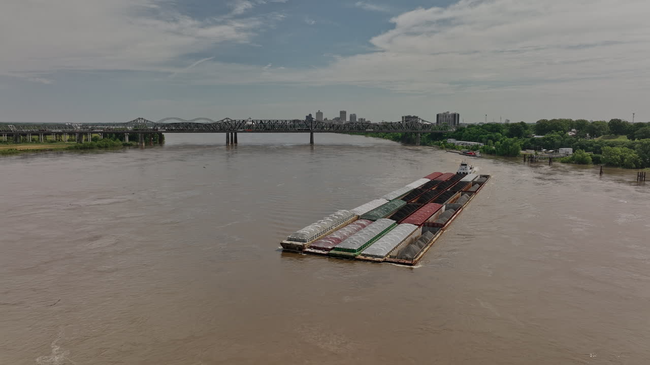멤피스 테네시 공중 v53 리버스 플라이오버는 미시시피 강 내륙 수로에서 유출된 호퍼 바지선을 밀고 있는 예인선을 캡처하여 교량과 도시 경관을 볼 수 있습니다 - 매빅 3 시네로 촬영 - 2022년 5월
