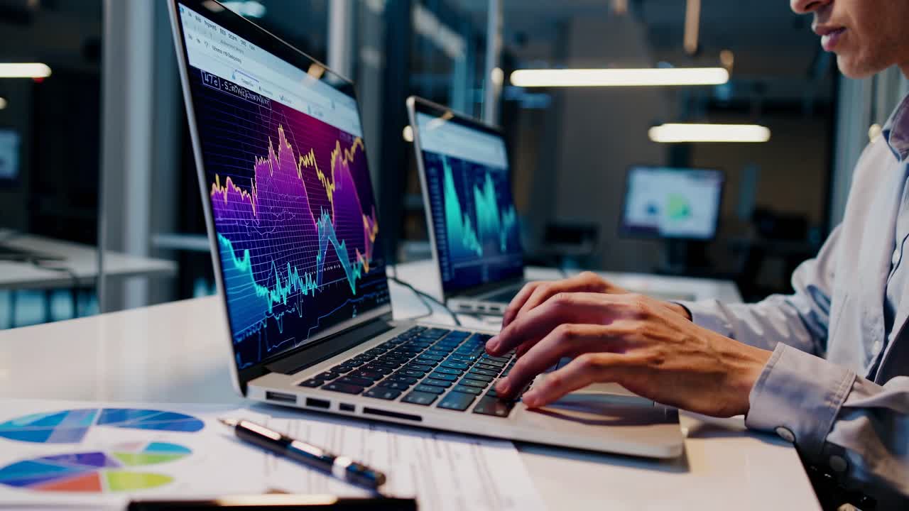 Low-angle shot of laptops displaying stock market graphs in a modern office
