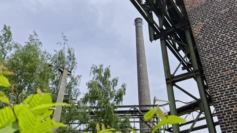 old industrial structures with pipes, chimney and brick buildings overgrown with nature